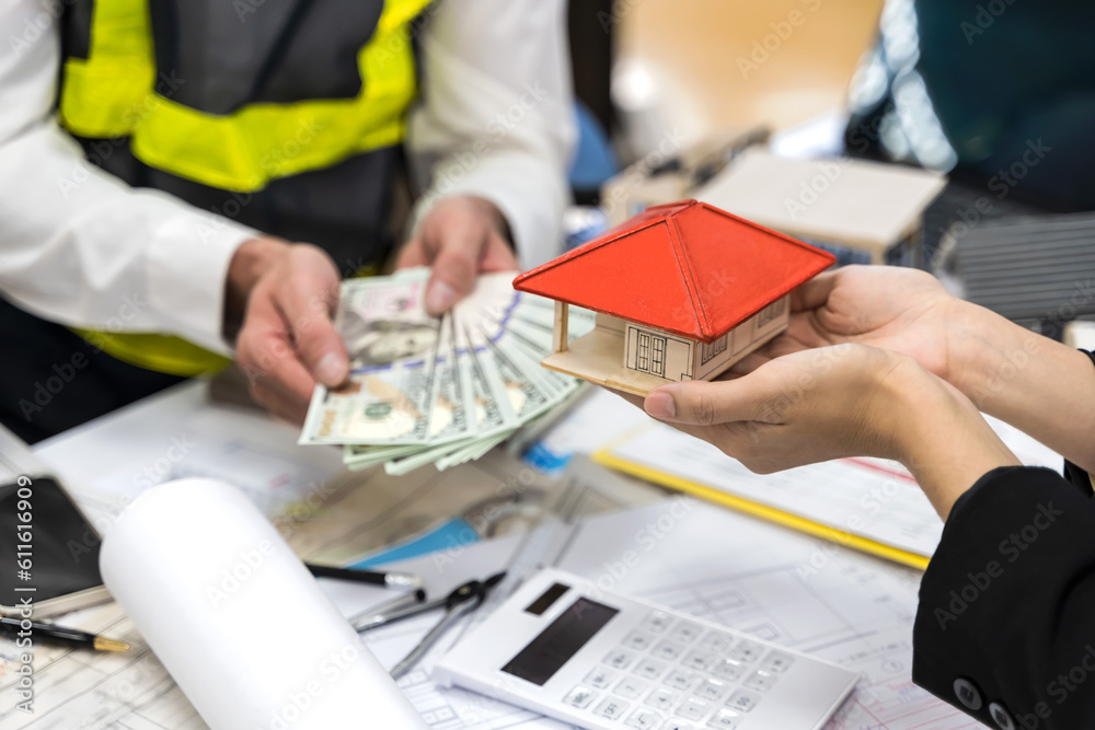 Fototapeta premium Close up hands holding banknotes and house model , real estate and loaning concept