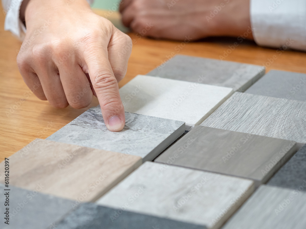 Architect hand choosing and pointing at stone material samples or tile texture collection on the table in studio. Designer working for interior architecture and furniture design project. Architect hand choosing and pointing at stone material samples or tile texture collection on the table in studio. Designer working for interior architecture and furniture design project.