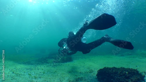 A diver with an underwater scooter makes a U-turn in front of the camera in back sunlight. photo