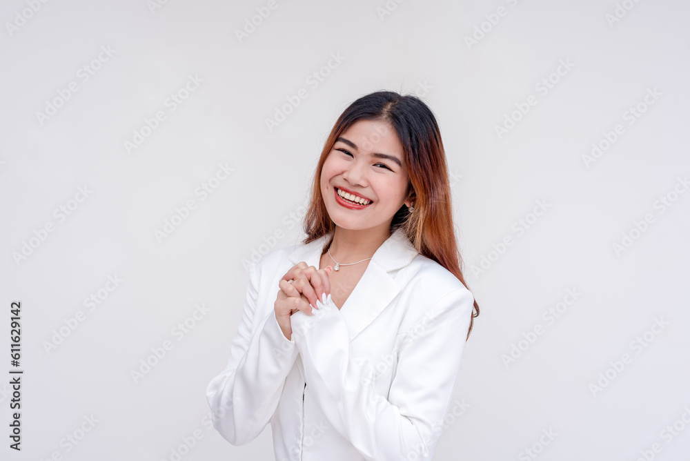 An optimistic young woman with hands clasped together while smiling at the camera. Isolated on a white background. An optimistic young woman with hands clasped together while smiling at the camera. Isolated on a white background.