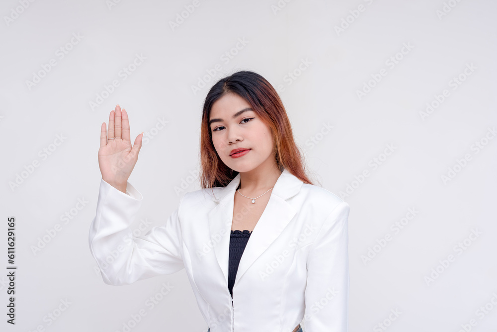 A serious young woman with one hand raised as an act of taking oath. Isolated on a white background. A serious young woman with one hand raised as an act of taking oath. Isolated on a white background.
