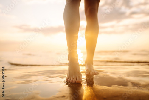 Woman leg close up walking on sand relaxing in beach at sunset. Sexy lean and tanned legs. Summer holidays.