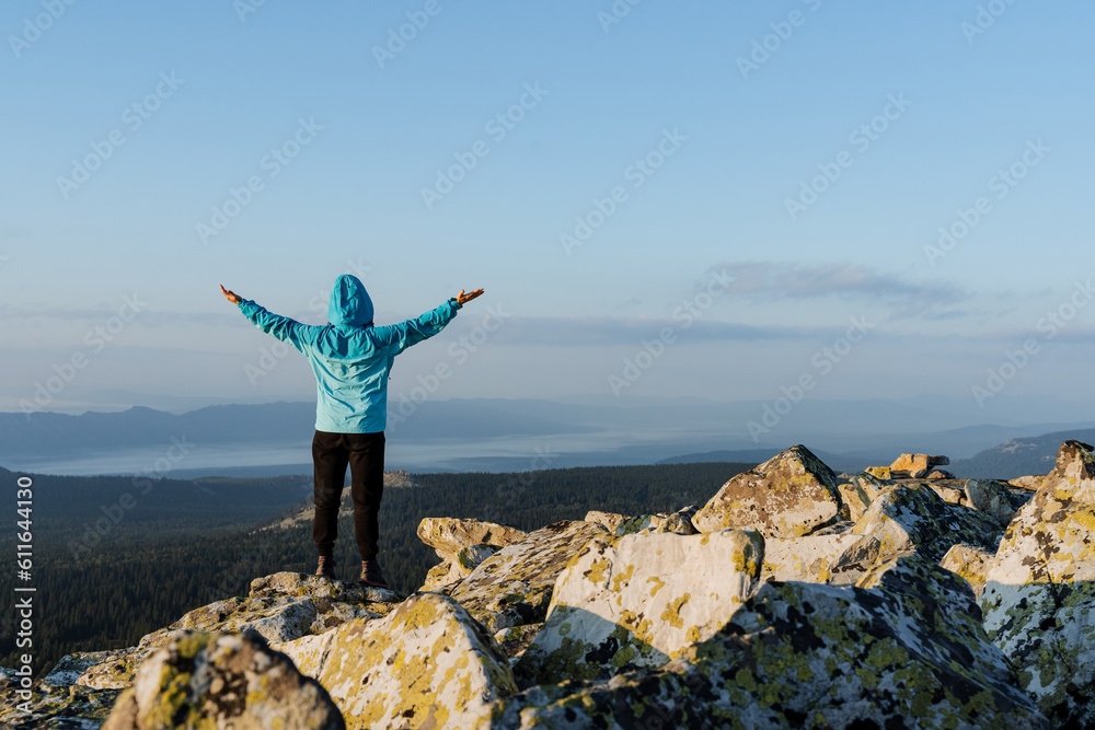 Obraz premium A feeling of delight and victory, climbing to the highest peak of the mountain, a person stands on a stone with his hands to the sides, Prayer to heaven, enjoy the beauty of nature.