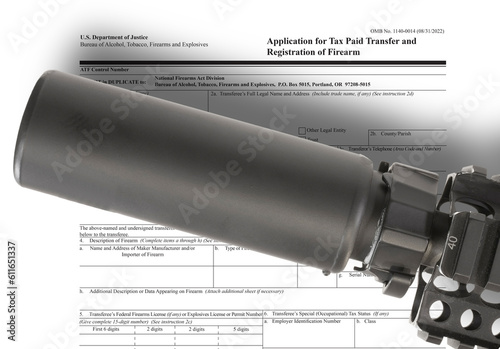 Public domain ATF form to own a suppressor in the background with silencer above photo