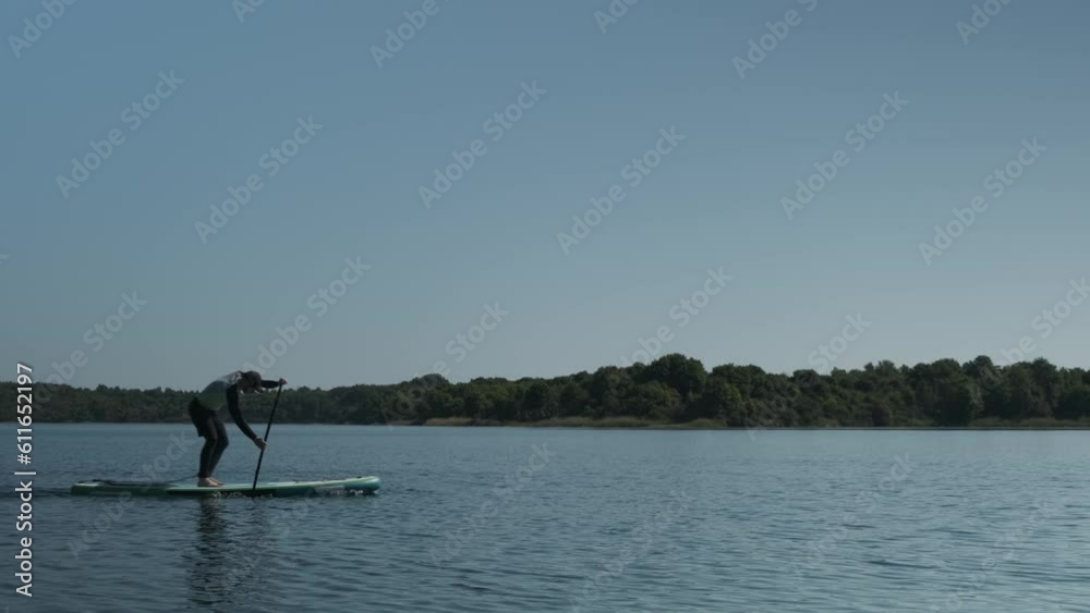 Man paddling on stand up paddle board on lake. SUP boarding 