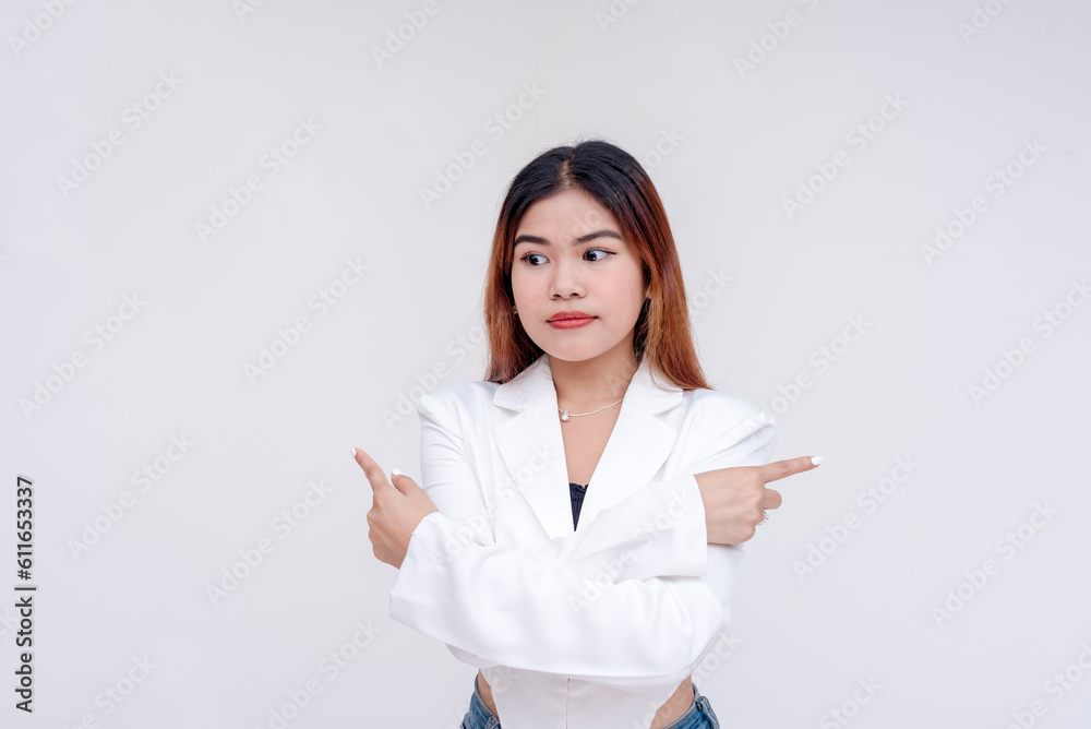 An unsure young woman looking down with her arms crossed while fingers pointing towards opposite direction. Isolated on a white background. An unsure young woman looking down with her arms crossed while fingers pointing towards opposite direction. Isolated on a white background.