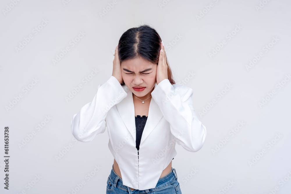 An overwhelmed young woman covering her ears in distress with eyes