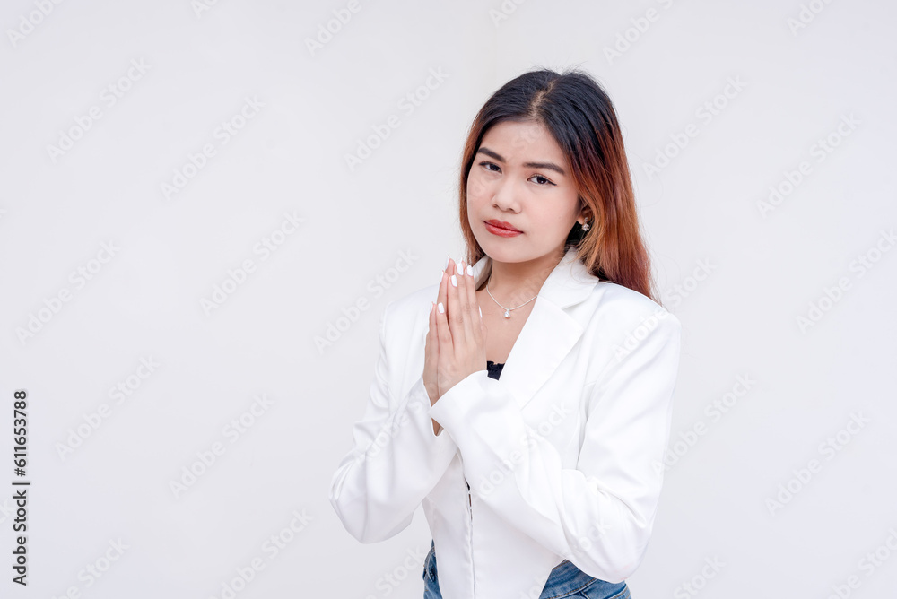 An intense and serious young woman looking straight at the camera with her hands clasped together. Isolated on a white background. An intense and serious young woman looking straight at the camera with her hands clasped together. Isolated on a white background.