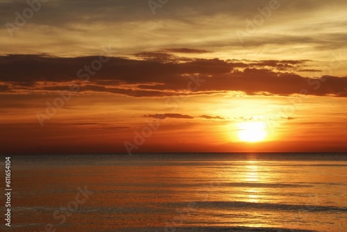 sun sets behind the horizon, a beautiful sea sunset. view low over the water. Bright red, orange sky over the ocean