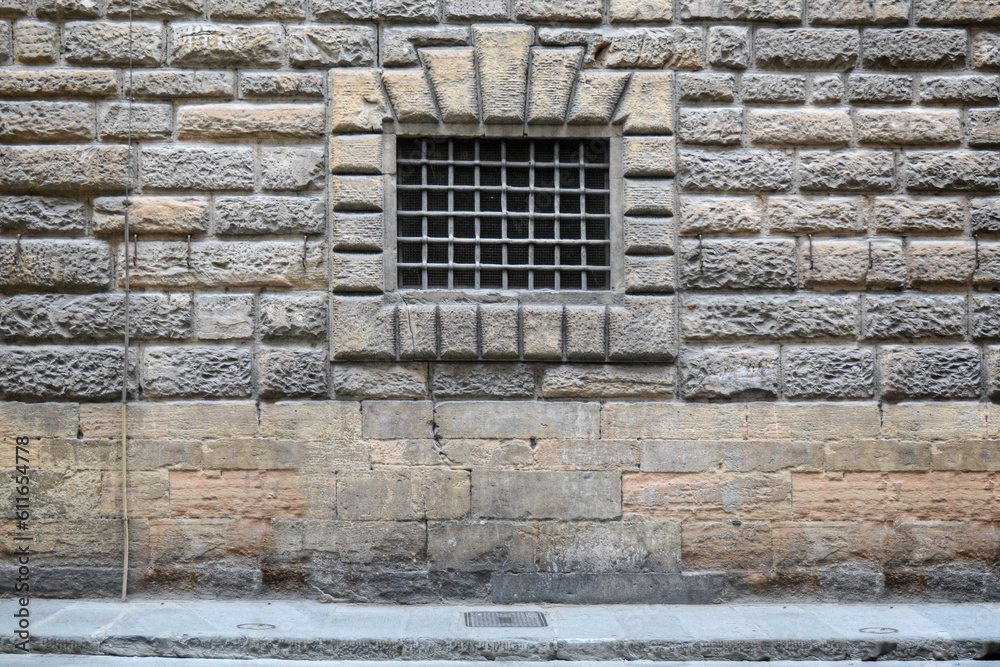A frontal photo of a massive window on a stone facade on a building in the city of Florence A frontal photo of a massive window on a stone facade on a building in the city of Florence