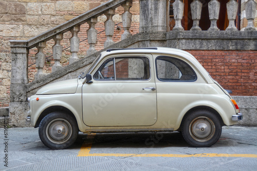 Fototapeta Naklejka Na Ścianę i Meble -  A side view of an small Italian car and an old facade in the background  