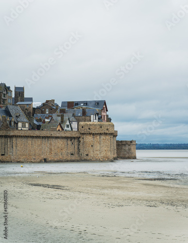 Partie basse de la muraille du Mont-Saint-Michel avec d'anciennes maisons médiévale. Devant, du sable à marée basse. © ELD