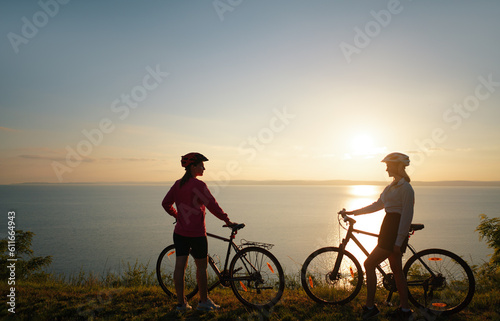 Two women with bicycles on the sea or lake shore
