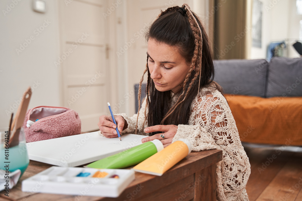 Awesome woman concentrated on painting while sitting at the table and enjoying favourite hobby Awesome woman concentrated on painting while sitting at the table and enjoying favourite hobby