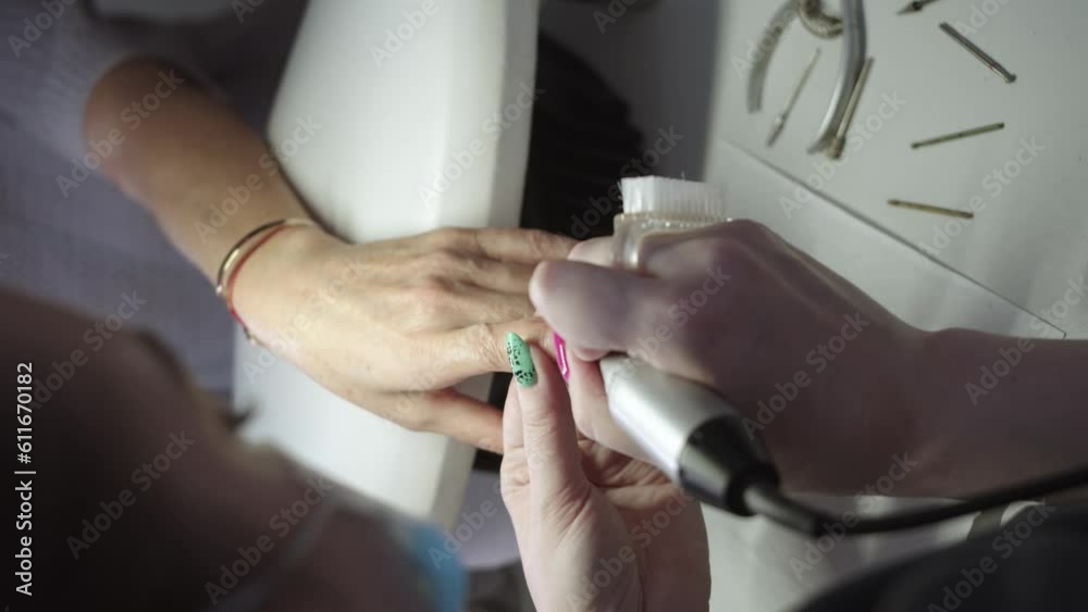 Manicure procedure - a woman treats the nail plate with a device Manicure procedure - a woman treats the nail plate with a device