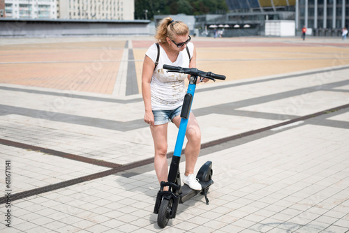 A woman is trying to figure things out, she is reading instructions on how to use an electric scooter for rent, woman urgently needs to get to another part of city and she rents a scooter