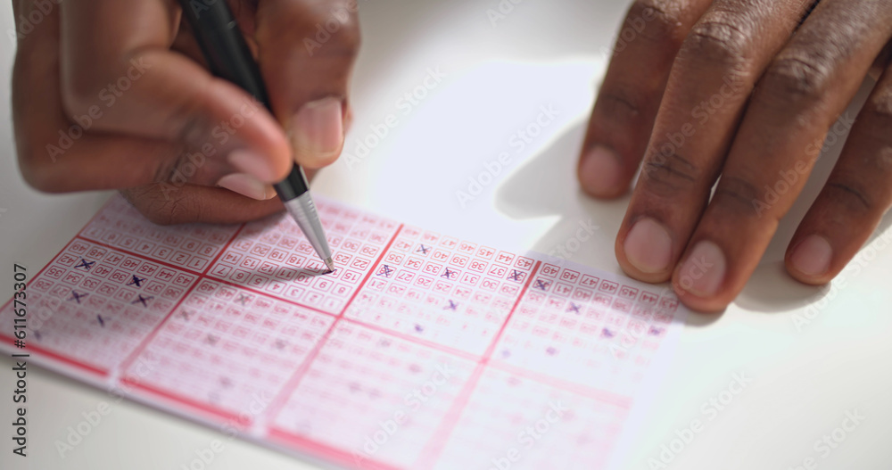 Person's Hand Marking Number On Lottery Ticket Person's Hand Marking Number On Lottery Ticket