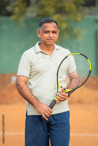 Happy smiling indian senior men with racquet and ball looking camera at tennis court - concept of confident, successful and relaxation © WESTOCK
