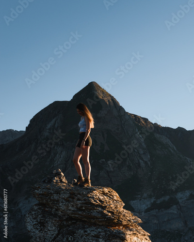 young girl having fun on a rock at sunset in the mountains during her trekking through the Pyrenees © Larraend Fotografía