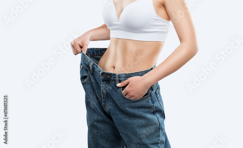 A young girl wears jeans that become large after weight loss and diet. Reducing excess weight. Healthy lifestyle.