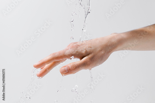 Water pouring on a woman's hand on a gray isolated background. The concept of skin hydration and moisture enrichment, anti-aging care. Image for your design