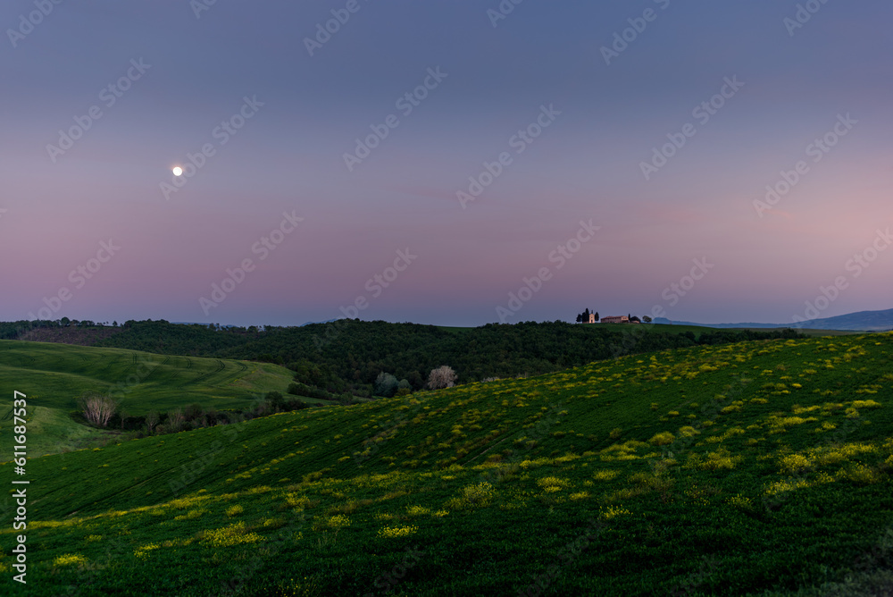 Obraz premium View of the Vitaleta Chapel and the surrounding hills of the Orcia Valley near San Quirico d'Orcia under the moon at sunset