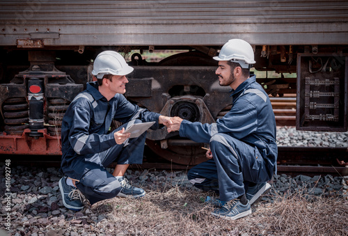 Engineer railway posing hand shake best cooperation inspection, checking train testing and checking railway work on railroad station Engineer wearing safety uniform and safety helmet in work.
