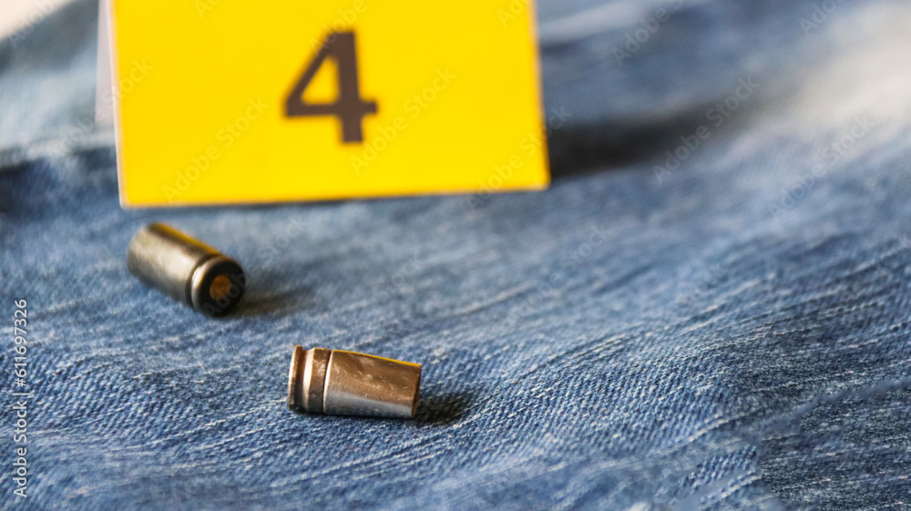 Pistol bullet shells on blur blue jeans and number four display in background, concept for criminal and investigation. soft focus Pistol bullet shells on blur blue jeans and number four display in background, concept for criminal and investigation. soft focus