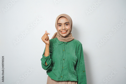 A smiling young Asian Muslim woman dressed in casual showing gesturing Korean love