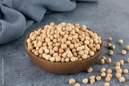 Raw chickpeas in wooden bowl on blue background. Superfood. 