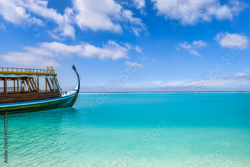 Fototapeta Naklejka Na Ścianę i Meble -  Wooden sailing boat in crystal clear tropical lagoon bay close to beach of deserted exotic island. Maldives Dhoni boat, vertical panorama as luxury travel landscape, amazing vacation wallpaper concept