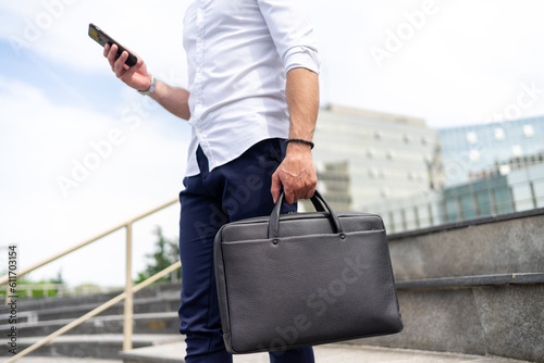 Close up photo of man standing on staircase and and holding a business bag
