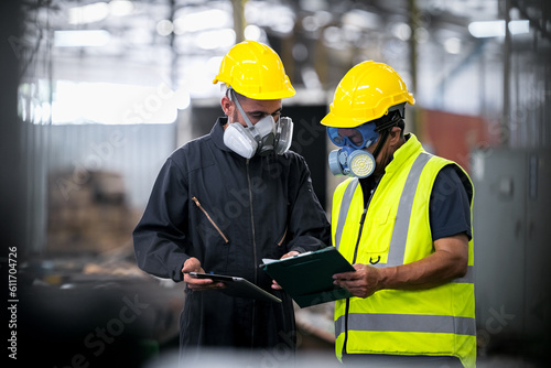 Two officers wearing gas masks, holding tablet and book, inspect the chemical spill site in an industrial warehouse to assess the damage, wearing gas masks, inspecting and evaluating toxicity of leak. photo