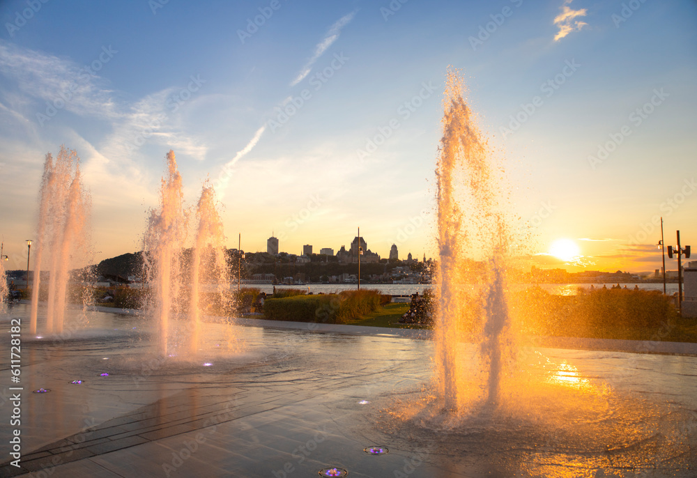 Naklejka premium Water fountains backlit by an orange sunset