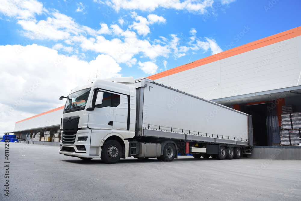 white truck in front of the warehouse, a loading truck