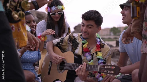 Group of musician friends having fun, singing and playing the guitar on the beach. Concept of community playing music at a festival. photo