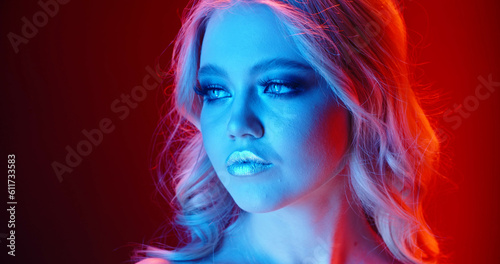 High Fashion model metallic silver lips woman in colorful bright neon blue and purple lights posing in studio, beautiful girl, trendy glowing make-up, colorful make up. Glitter Vivid neon makeup