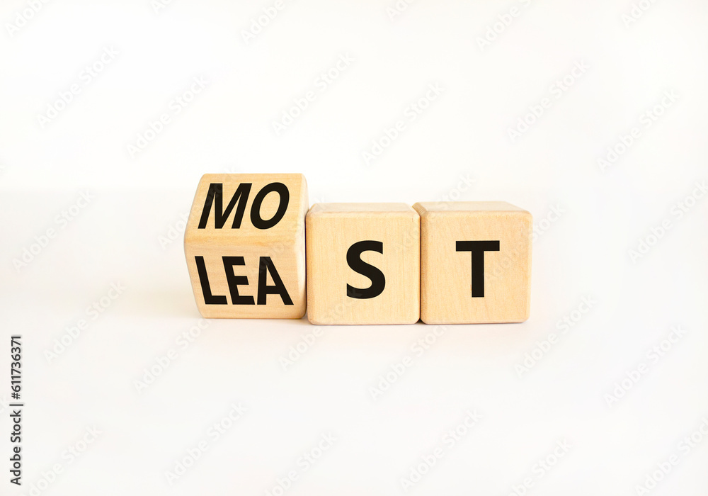 Most or least symbol. Businessman turns wooden cubes and changes the word Least to Most. Beautiful white table white background. Copy space. Business and most or least concept. Most or least symbol. Businessman turns wooden cubes and changes the word Least to Most. Beautiful white table white background. Copy space. Business and most or least concept.