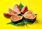 figs with green leaves on yellow background, healthy tropical fruit