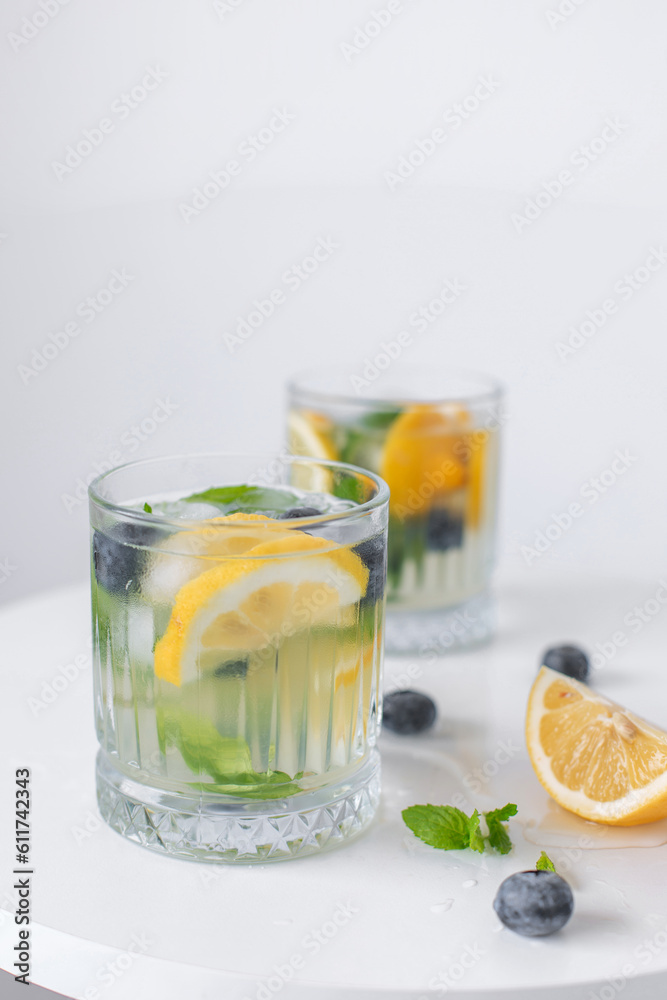 Fototapeta premium lemonade in a glass and lemons on a white background. Summer refreshing drink. Cold detox water with lemon