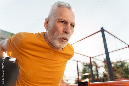 Retired male athlete performing pull ups on horizontal bar