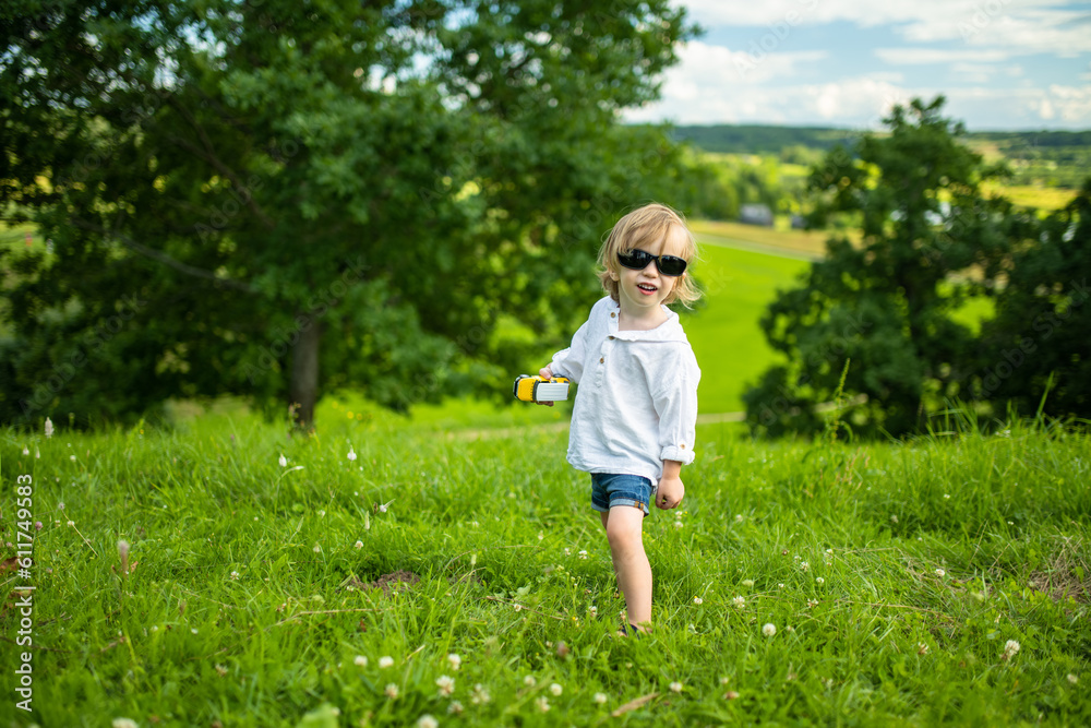 Adorable toddler boy having fun outdoors on sunny summer day. Child exploring nature. Summer activities for kids. Adorable toddler boy having fun outdoors on sunny summer day. Child exploring nature. Summer activities for kids.