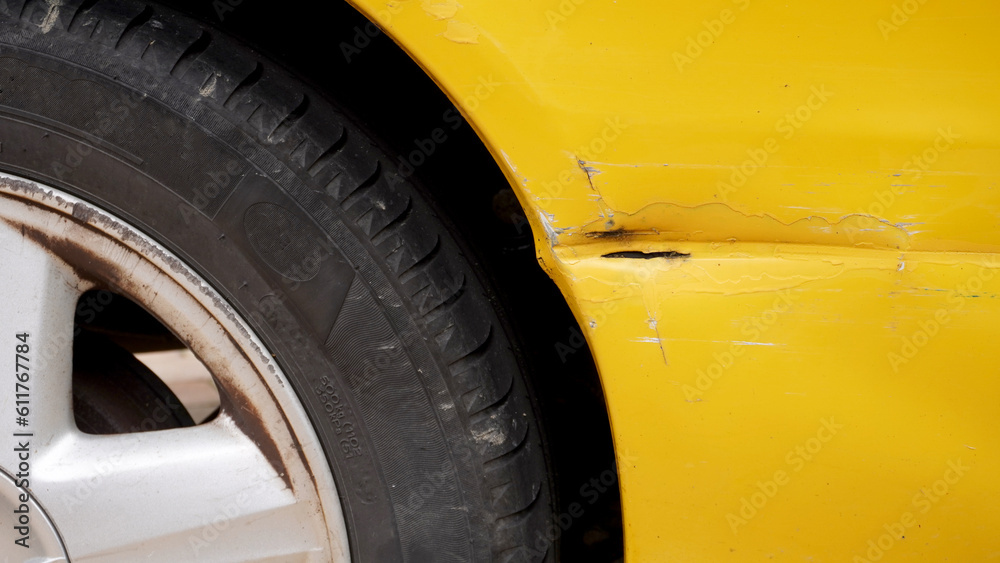  a deep scratch on the body of a yellow car after a repair attempt, in an impromptu way