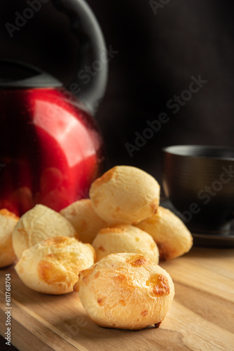 Cheese bread, Basket with cheese bread lying on rustic wood, red kettle and accessories, dark background, selective focus.