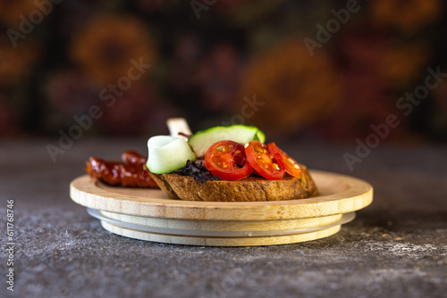 close-up of black bread bruschetta with tomato and cucumber on a wooden plate