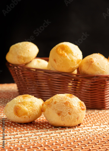Cheese bread, Basket with cheese bread lying on a wooden woven mat, dark background, selective focus.