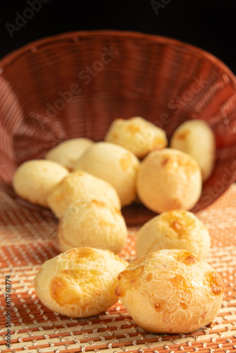 Cheese bread, Basket with cheese bread lying on a wooden woven mat, dark background, selective focus.