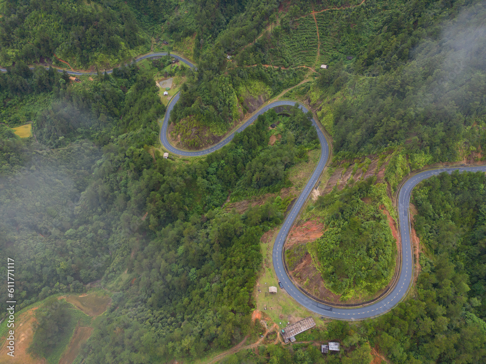 Aerial view of cars driving on curved, zigzag curve road or street on mountain hill with green natural forest trees in rural area of Nan, Thailand. Transportation. Aerial view of cars driving on curved, zigzag curve road or street on mountain hill with green natural forest trees in rural area of Nan, Thailand. Transportation.