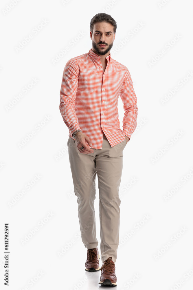 confident young man with beard holding hand in pocket and walking confident young man with beard holding hand in pocket and walking