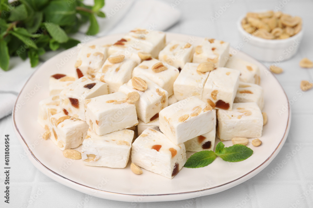 Pieces of delicious nutty nougat on plate, closeup